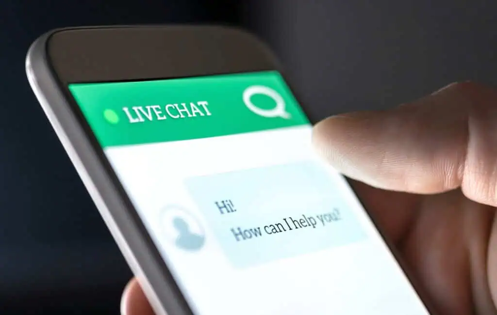 Hand holding a smartphone showing “How can I help you?” and a short message.