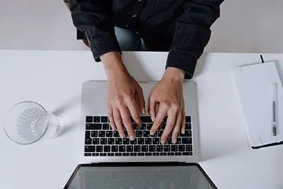 Image showing a desk with an macbook with a woman typing on the computer